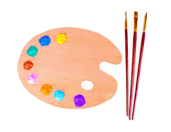 Wooden art palette with blobs of paint and a brush on white back — Stock Photo, Image
