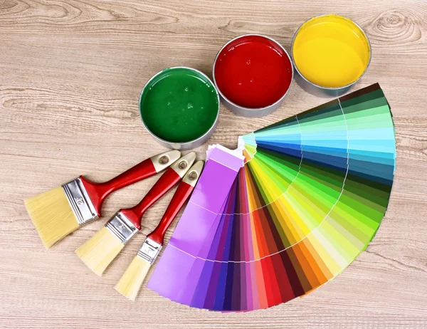 Öppna burkar med ljusa färger, penslar och palett på träbord — Stockfoto