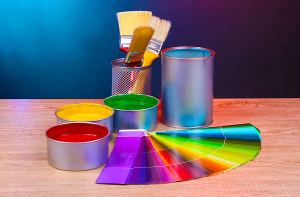 Open cans with bright colors, brushes and palette on wooden table — Stock Photo, Image