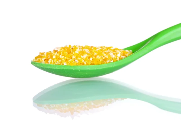 Grãos de milho em colher de plástico verde isolado em branco — Fotografia de Stock