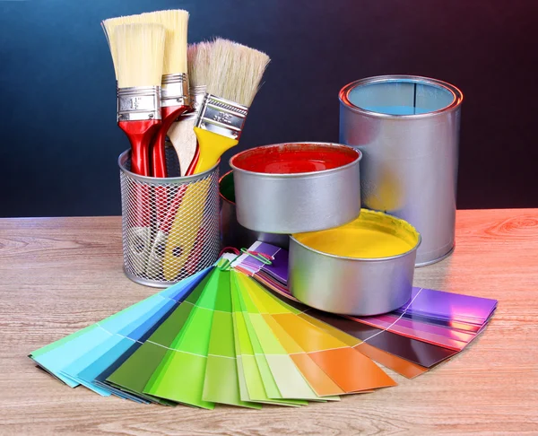 Open blikjes met felle kleuren, -borstels en palet op houten tafel — Stockfoto