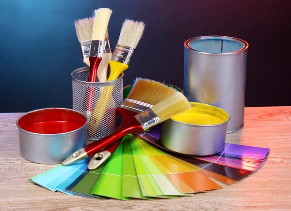 Open blikjes met felle kleuren, -borstels en palet op houten tafel — Stockfoto