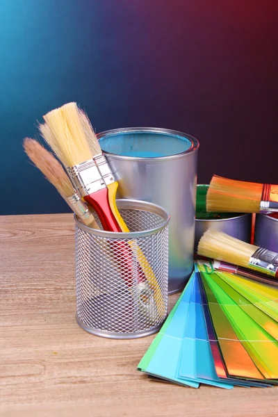 Otwartej puszki w jasnych kolorach, szczotki i palety na drewnianym stole — Zdjęcie stockowe