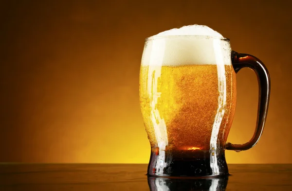 Mugg öl på en gul bakgrund — Stockfoto