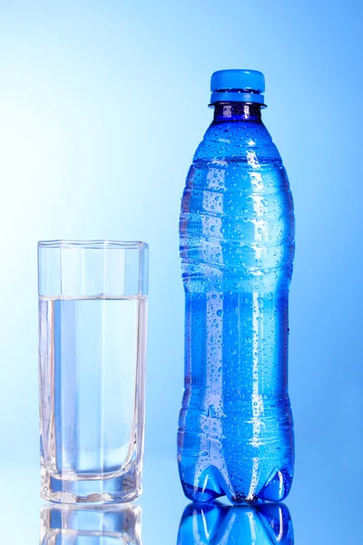 Garrafa de água com vidro sobre fundo azul — Fotografia de Stock