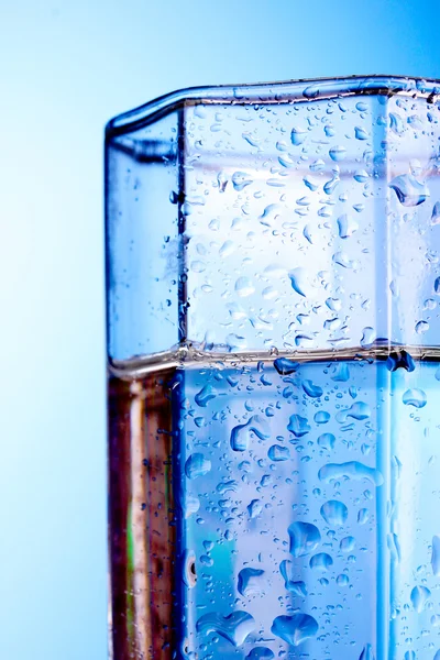 Vidrio con agua sobre fondo azul — Foto de Stock