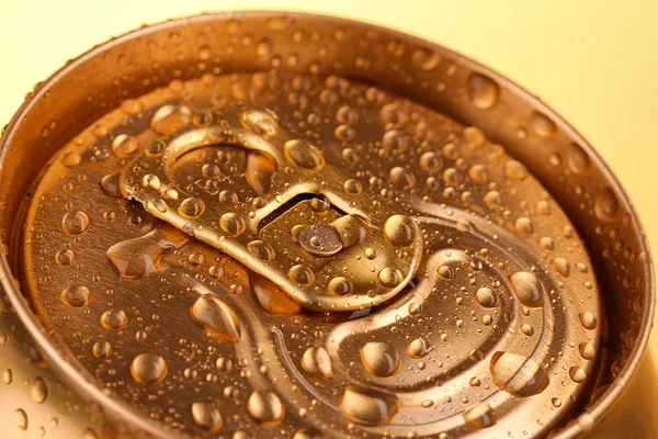 Золотое металлическое пиво с капельками воды на желтом фоне — стоковое фото