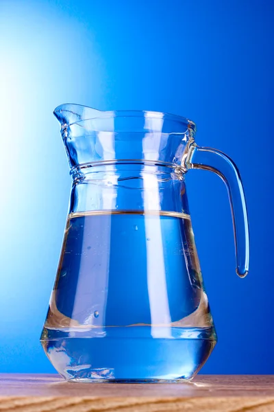 Džbán vody na modrém pozadí — Stock fotografie