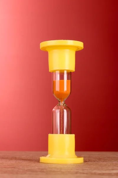 Gult timeglass på rød bakgrunn – stockfoto