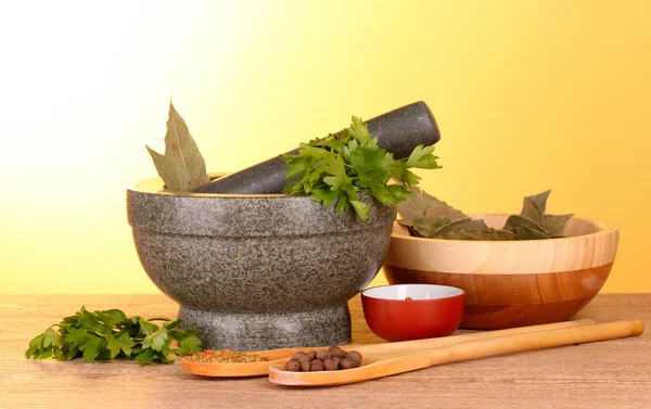 Mortar and pestle, bowls, parsley and pepper on yellow backgroun — Stock Photo, Image