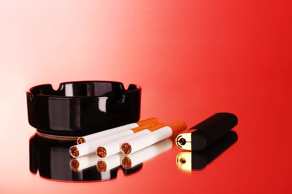 Cigarettes, ashtray and lighter on red background — Stock Photo, Image