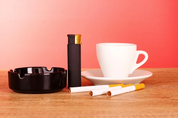 Sigaretten, asbak en kopje koffie op rode achtergrond — Stockfoto