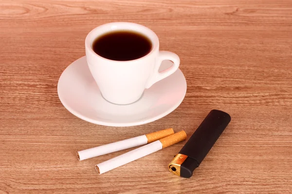 Cigarettes and cup of coffee on wooden background — Stock Photo, Image