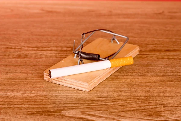 Cigarette in mousetrap on wooden background — Stock Photo, Image