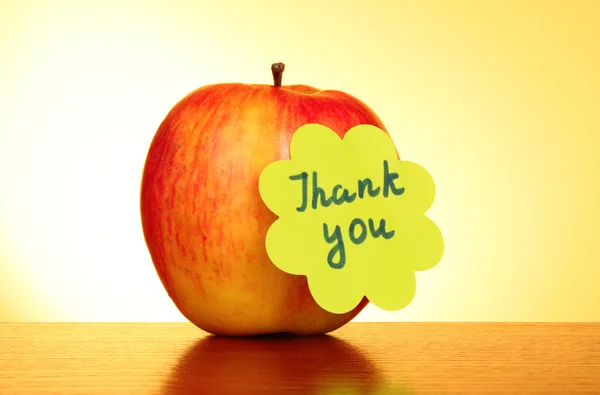 Apple with "Thank you" label on yellow background — Stock Photo, Image