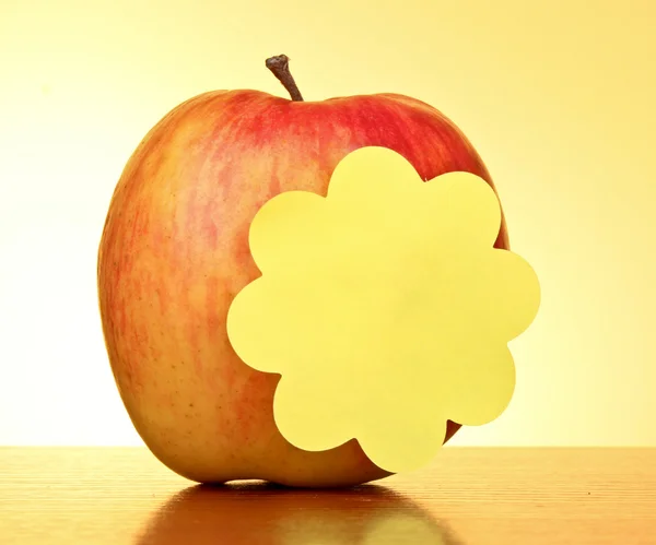 Apple with empty sticker on yellow background — Stock Photo, Image