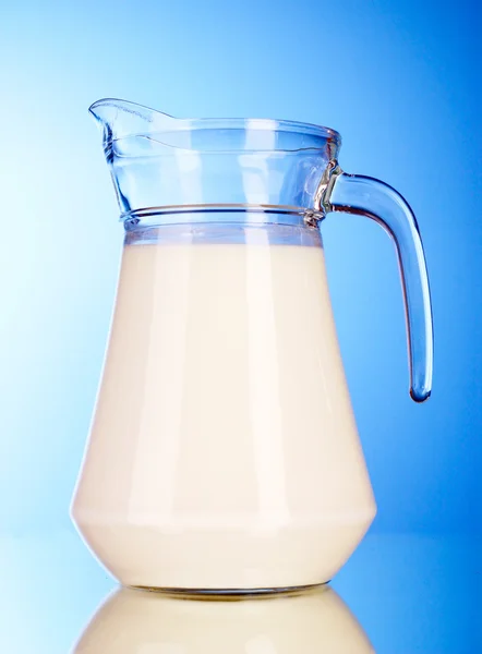 Pitcher with milk on blue background — Stock Photo, Image