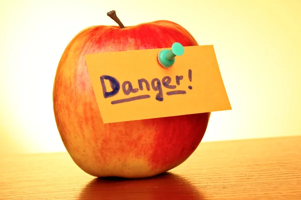 "tehlike" etiketi ile sarı zemin üzerine elma — 스톡 사진