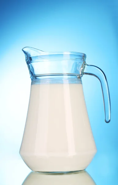 Pitcher with milk on blue background — Stock Photo, Image