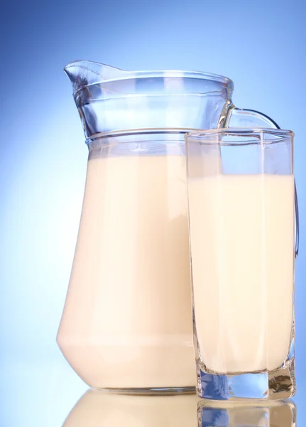 Werper en glas met melk op blauwe achtergrond — Stockfoto