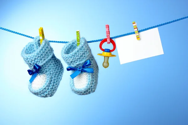 stock image Baby booties, nipple and white card on a blue background