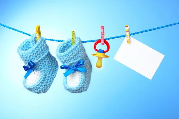 Baby booties, nipple and white card on a blue background — Stock Photo, Image