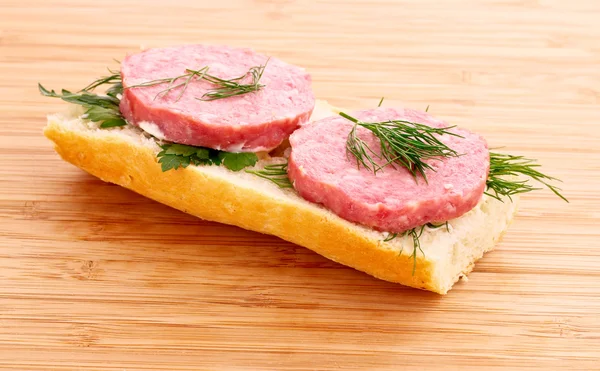 Sausage on bread on wooden table — Stock Photo, Image