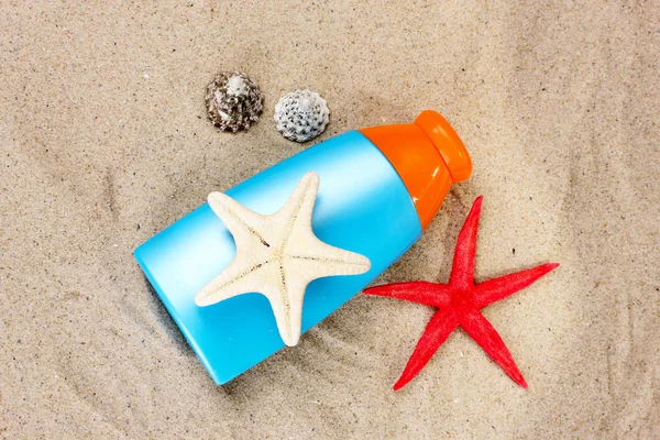 Sonnencreme in Flaschen, Muscheln und Seesternen auf Sand — Stockfoto