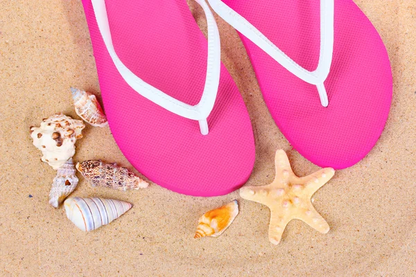 Strandschuhe, Muscheln und Seesterne auf Sand — Stockfoto