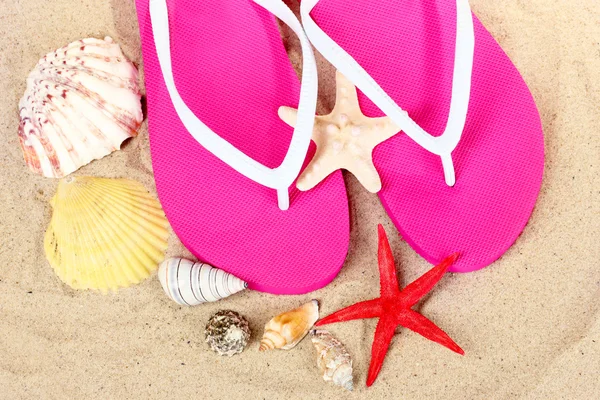 Plaj ayakkabı, kabukları ve denizyıldızı kum üzerinde — Stok fotoğraf