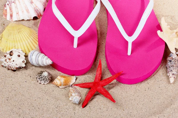 Plaj ayakkabı, kabukları ve denizyıldızı kum üzerinde — Stok fotoğraf