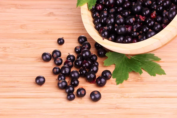 Fresh blackcurrant in bowl on wooden surface — Stock Photo, Image