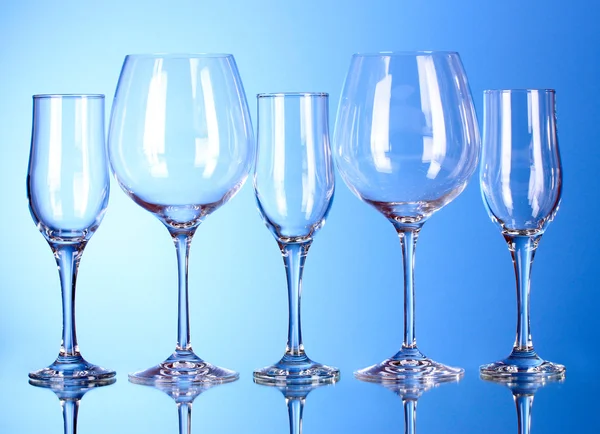 Kilka pustych kieliszków do wina na niebieskim tle — Zdjęcie stockowe