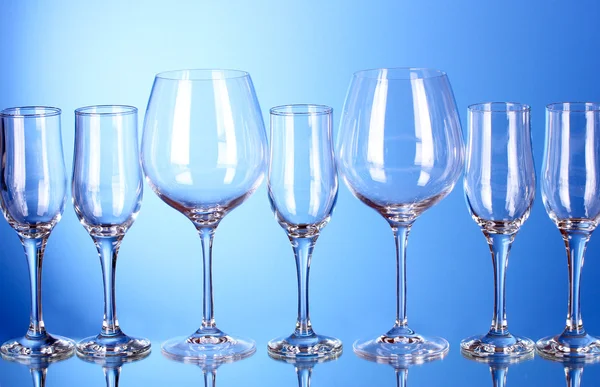 Málo prázdné sklenice na víno na modrém pozadí — Stock fotografie
