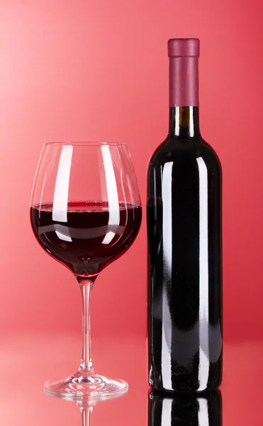 Vin flaska och glas på röd bakgrund — Stockfoto