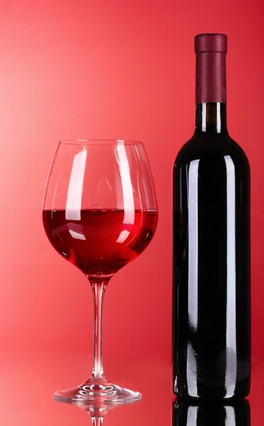 Wijn fles en glas op rode achtergrond — Stockfoto