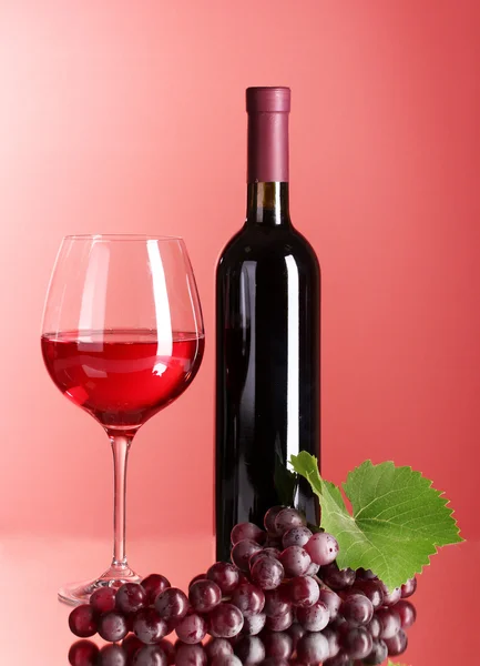 Bottiglia di vino e bicchiere su sfondo rosso — Foto Stock