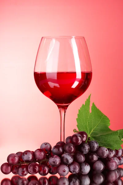 Μπουκάλι κρασί και γυαλί, σε κόκκινο φόντο — Φωτογραφία Αρχείου