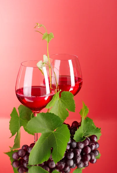 Garrafa de vinho e vidro no fundo vermelho — Fotografia de Stock