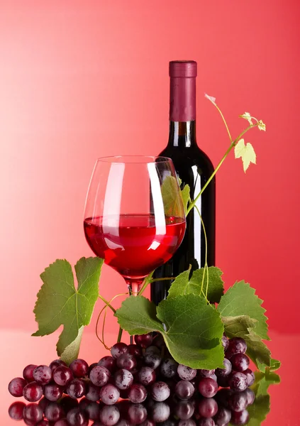 Şarap şişesi ve kırmızı zemin üzerine cam — Stok fotoğraf