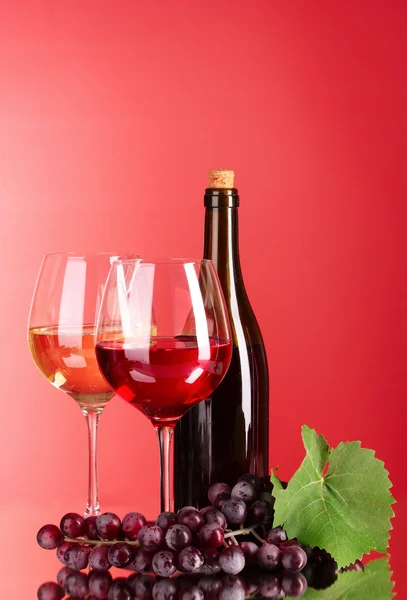 Botella de vino y copa sobre fondo rojo — Foto de Stock