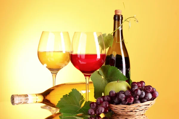 Red wine and fruits on yellow background