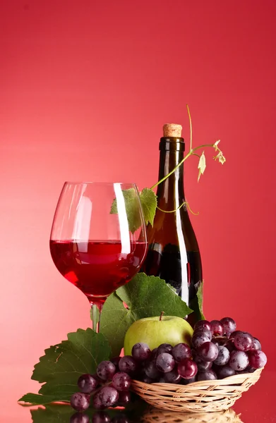Şarap ve meyve kırmızı zemin üzerine — Stok fotoğraf