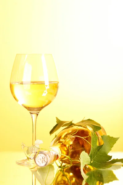Vinho e folhas de uva no fundo amarelo — Fotografia de Stock