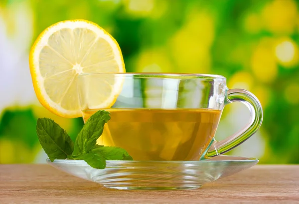 Čaj s citrónem na pozadí zelených listů — Stock fotografie