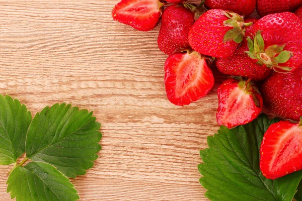 Viele Erdbeeren und Blätter auf Holzgrund — Stockfoto