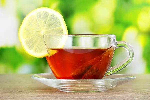 Tea with lemon on green leaves background — Stock Photo, Image