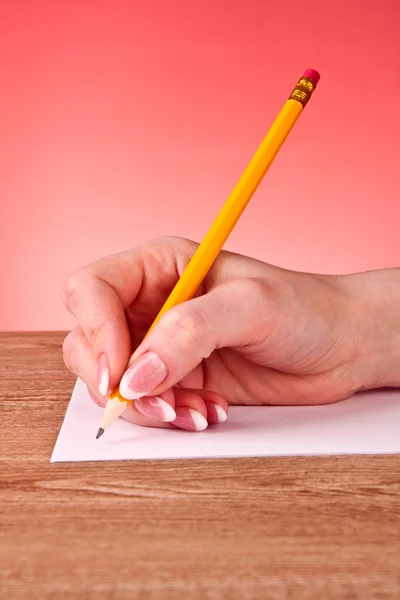 Kvinna hand skriva gul trä penna på papper — Stockfoto