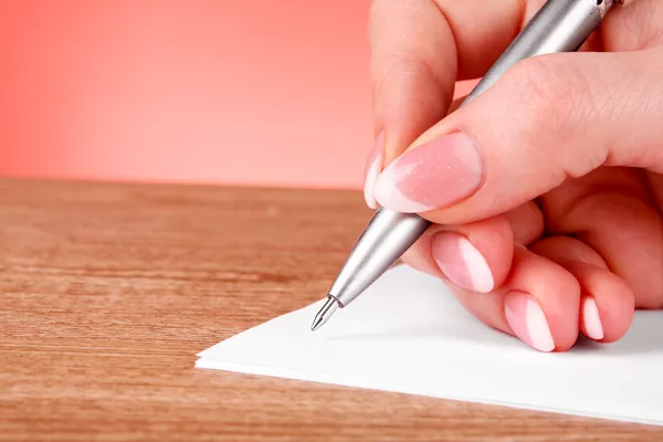 Ручка в руці, що пише на папері — стокове фото