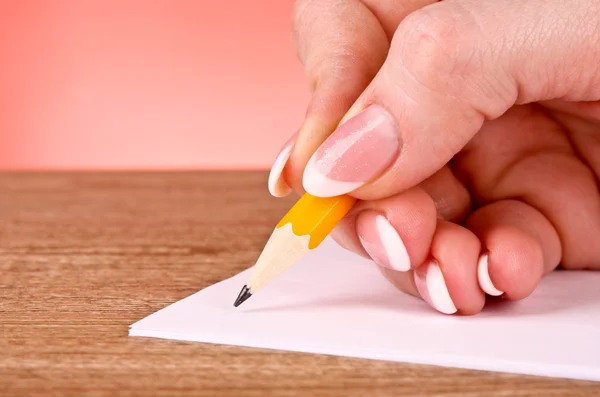 Mujer escritura a mano lápiz de madera amarillo sobre papel — Foto de Stock